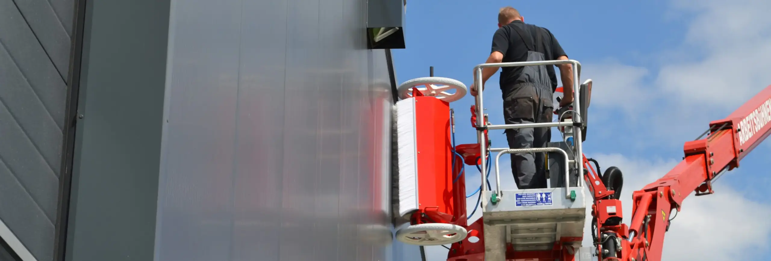 Reinigungsroboter facadeBRUSH h-line reinigt eine Gebäudefassade kontrolliert von einem Mitarbeiter
