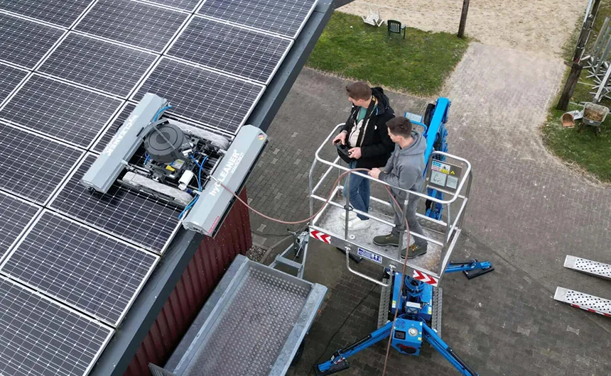 Zwei hyCleaner Mitarbeiter auf einem Gondelsystem steuern den Reinigungsroboter solarROBOT pro mit einer Fernbedienung