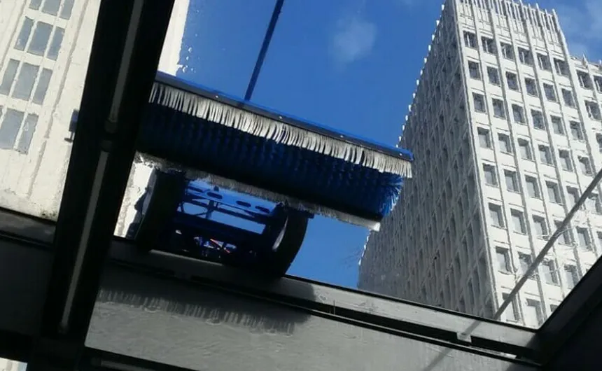 Blik van onderaf door een glazen dak waarop een reinigingsrobot werkt