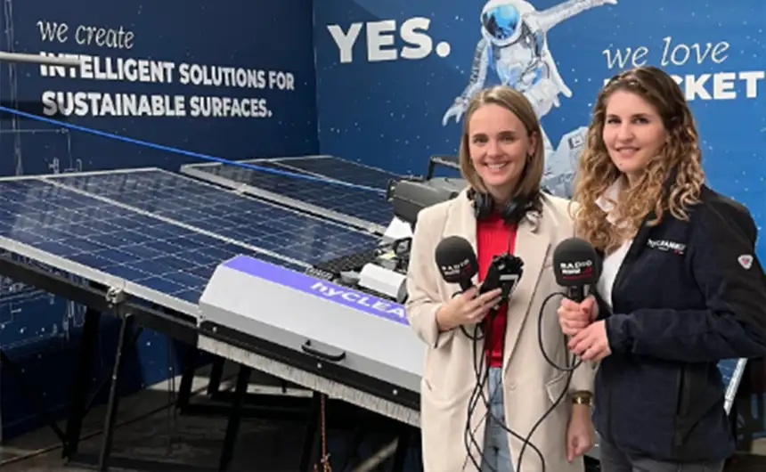 Two people with microphones in front of a hyCleaner information stand for a podcast